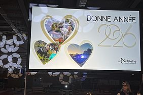 Ein Bildschirm mit einer "Bonne Année 2020"-Nachricht, umgeben von drei Herzformen mit Bildern und dem Logo von "La Madeleine".