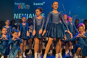 Eine Gruppe der Tanzgarde Blaue Funken tanzt auf der Bühne mit einem blauen Hintergrund.